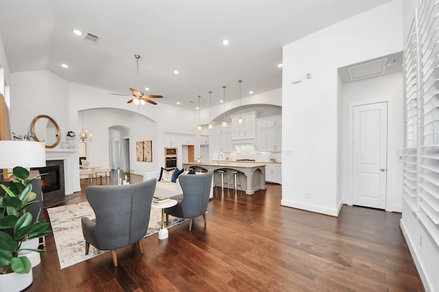 living room featuring ceiling fan, sink, lofted ceiling, and dark wood-type flooring