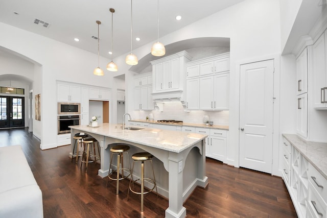 kitchen featuring white cabinetry, sink, hanging light fixtures, a kitchen island with sink, and appliances with stainless steel finishes