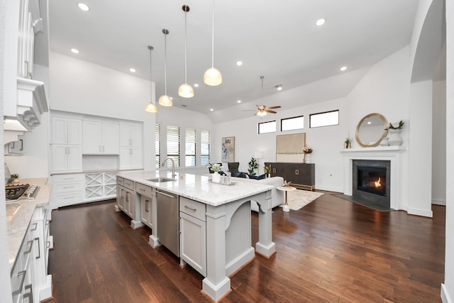 kitchen featuring light stone counters, ceiling fan, a spacious island, sink, and hanging light fixtures