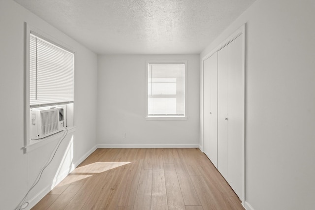 unfurnished bedroom featuring light wood-type flooring, a textured ceiling, and a closet