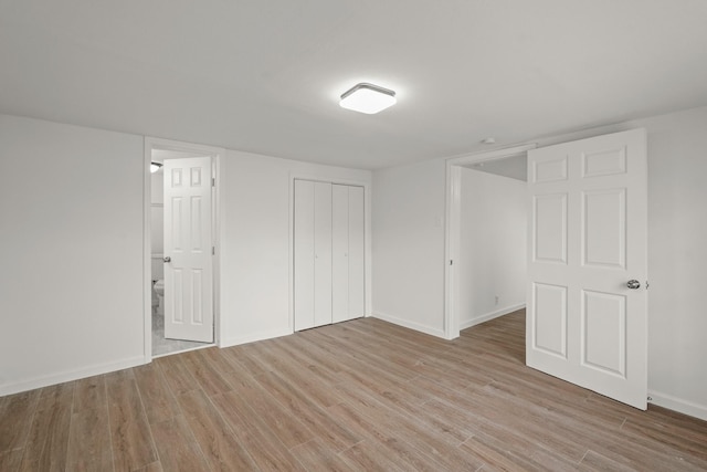 unfurnished bedroom featuring light hardwood / wood-style flooring and ensuite bath