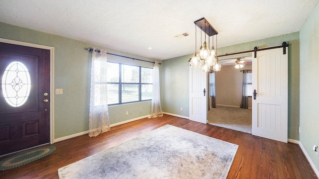 foyer with a barn door, ceiling fan, dark hardwood / wood-style flooring, and a textured ceiling