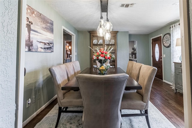 dining space with a textured ceiling and dark hardwood / wood-style floors