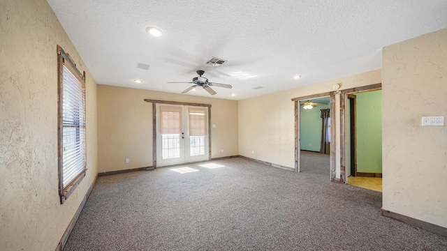 unfurnished room with carpet flooring, plenty of natural light, a textured ceiling, and french doors