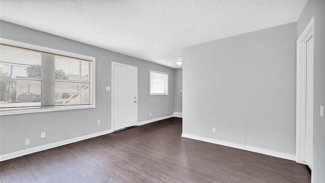 spare room with dark wood-type flooring and a healthy amount of sunlight