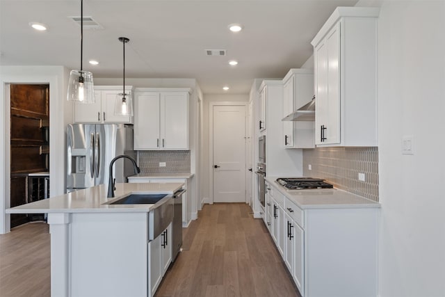 kitchen featuring backsplash, stainless steel appliances, pendant lighting, white cabinets, and light hardwood / wood-style floors