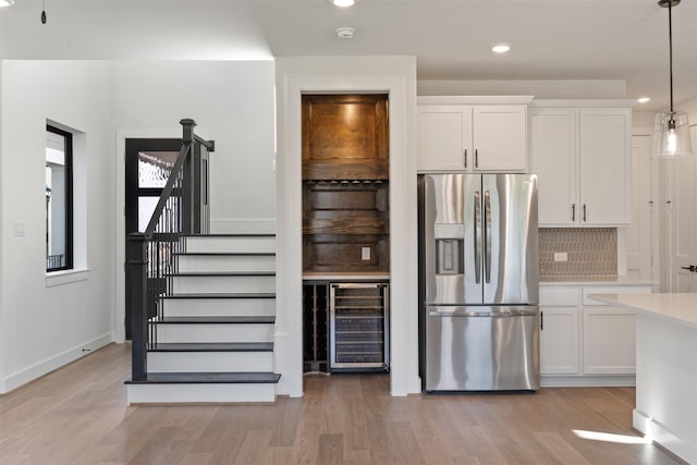 kitchen with white cabinetry, wine cooler, stainless steel fridge, decorative light fixtures, and decorative backsplash