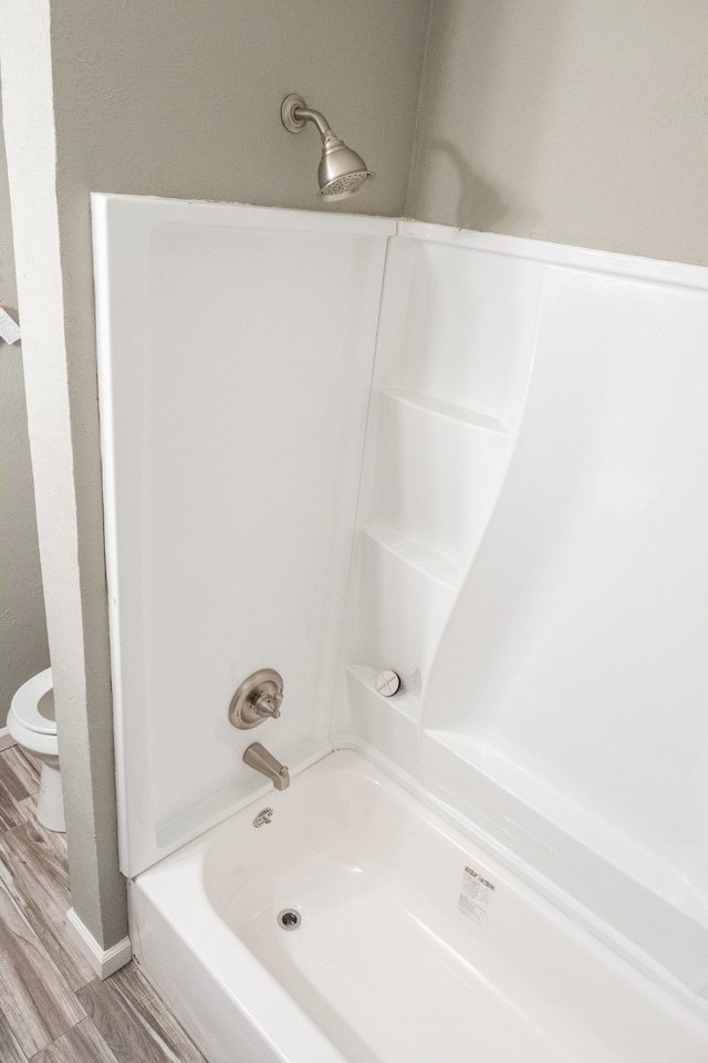 bathroom featuring hardwood / wood-style floors, shower / bathtub combination, and toilet