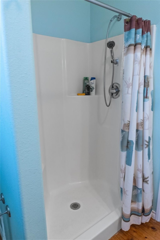 bathroom with a shower with curtain and wood-type flooring