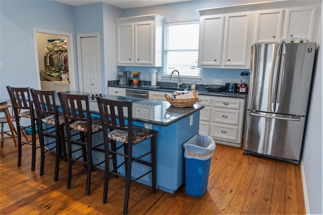 kitchen with white cabinets, appliances with stainless steel finishes, a breakfast bar, and a kitchen island