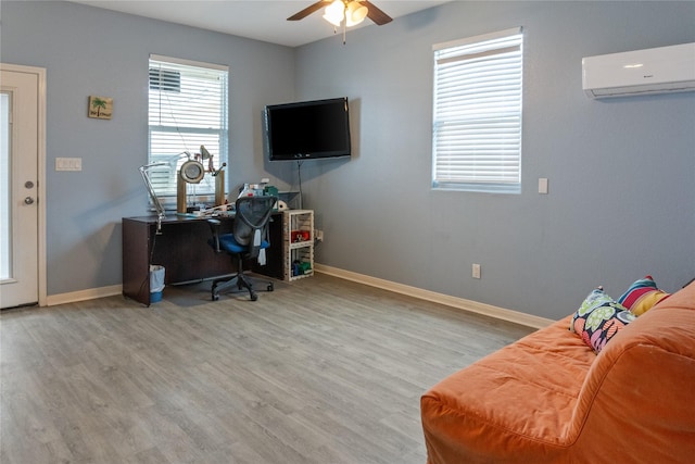 home office featuring ceiling fan, a wall unit AC, and light hardwood / wood-style flooring