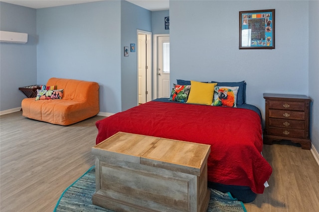 bedroom with a wall mounted air conditioner and hardwood / wood-style flooring