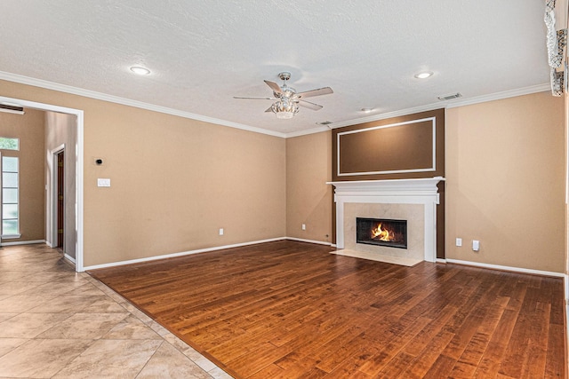 unfurnished living room with ceiling fan, light hardwood / wood-style flooring, crown molding, a textured ceiling, and a fireplace