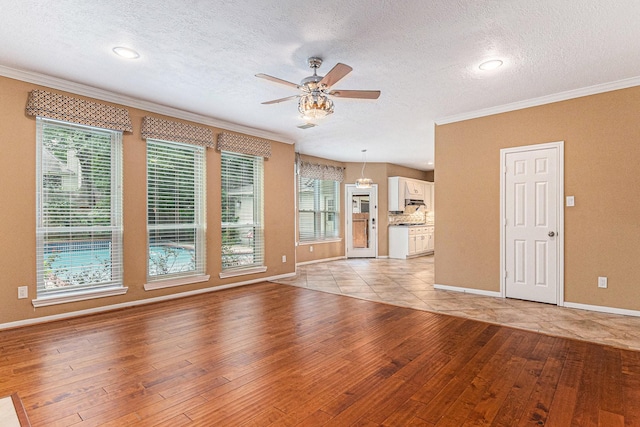 unfurnished living room with ceiling fan, light hardwood / wood-style flooring, crown molding, and a textured ceiling