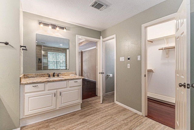 bathroom featuring a shower with curtain, vanity, wood-type flooring, and a textured ceiling