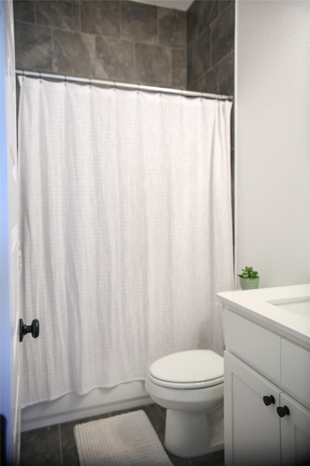 full bathroom featuring tile patterned flooring, vanity, toilet, and shower / bath combo with shower curtain