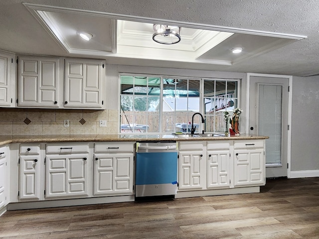 kitchen with light hardwood / wood-style floors, a raised ceiling, dishwasher, white cabinets, and sink