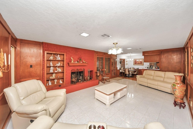 living room featuring a brick fireplace, built in features, a chandelier, a textured ceiling, and wooden walls