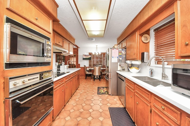 kitchen with hanging light fixtures, sink, black appliances, and an inviting chandelier