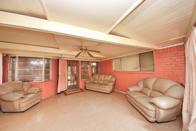 living room with ceiling fan, beamed ceiling, and brick wall