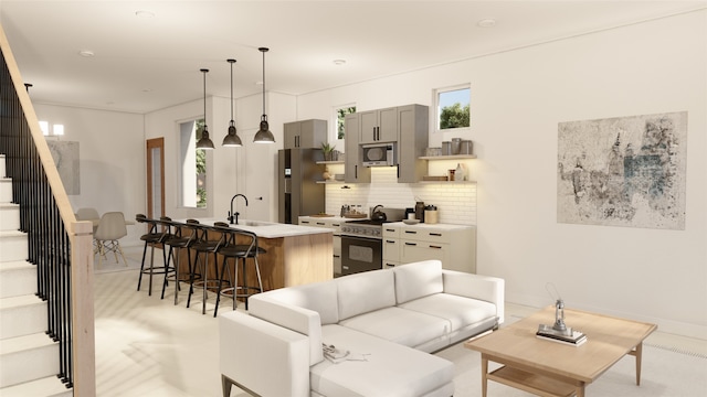 interior space featuring a kitchen island with sink, a kitchen breakfast bar, gray cabinets, appliances with stainless steel finishes, and tasteful backsplash