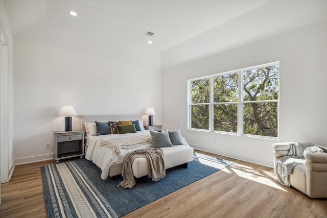 bedroom featuring hardwood / wood-style floors, lofted ceiling, and multiple windows