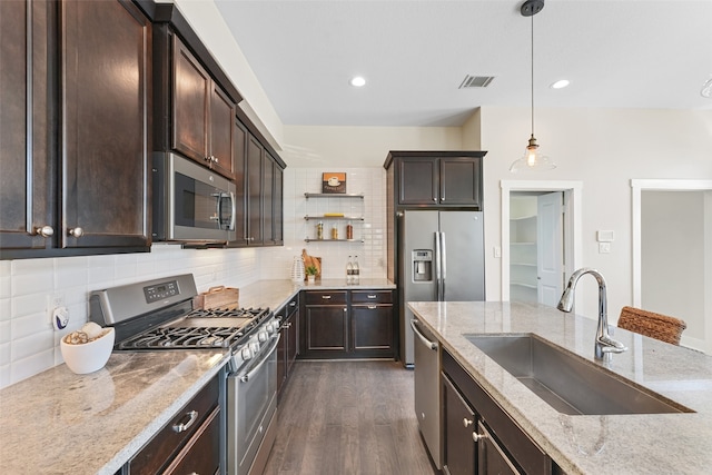 kitchen with light stone countertops, sink, hanging light fixtures, dark hardwood / wood-style floors, and appliances with stainless steel finishes