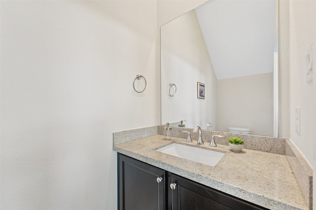 bathroom with vanity, toilet, and lofted ceiling