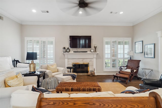 living room with ceiling fan, dark hardwood / wood-style flooring, a premium fireplace, and ornamental molding