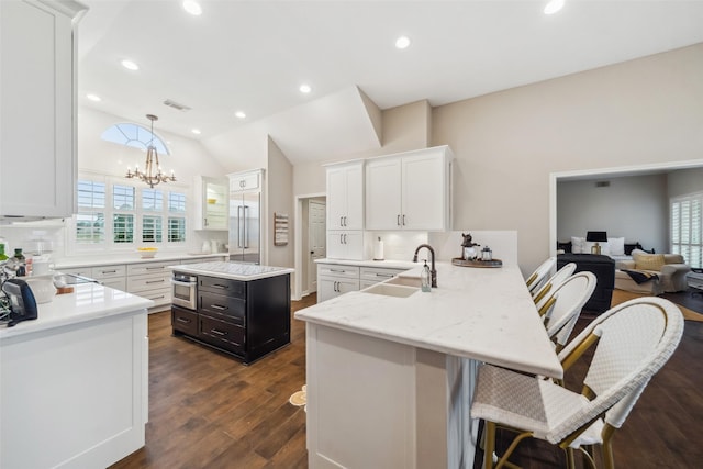 kitchen featuring kitchen peninsula, a breakfast bar, an inviting chandelier, white cabinets, and hanging light fixtures