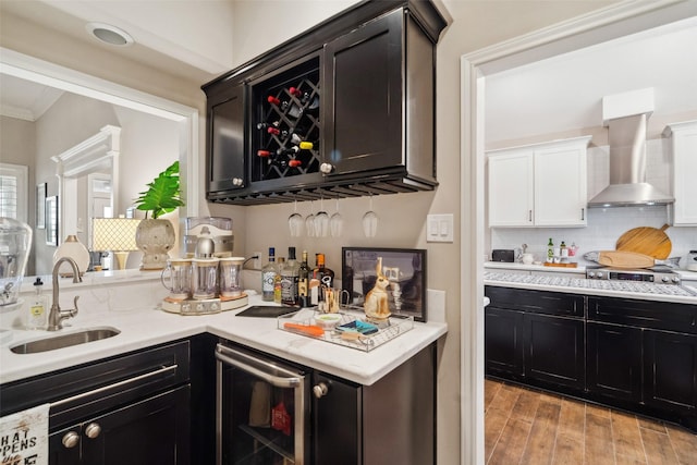 bar with ornamental molding, wall chimney exhaust hood, beverage cooler, sink, and stainless steel gas stovetop