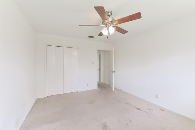 unfurnished bedroom featuring a closet, light colored carpet, and ceiling fan