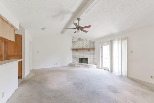 unfurnished living room with lofted ceiling with beams, a brick fireplace, ceiling fan, a textured ceiling, and light colored carpet