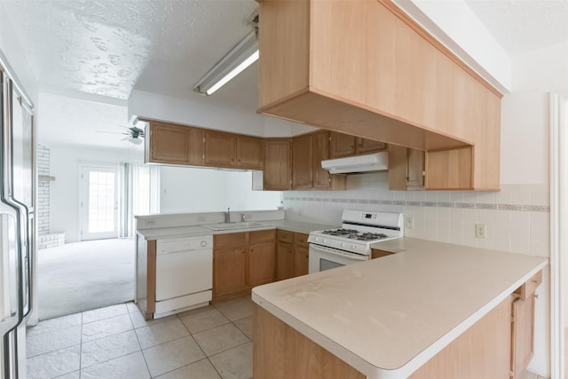 kitchen featuring white appliances, sink, ceiling fan, light tile patterned flooring, and kitchen peninsula