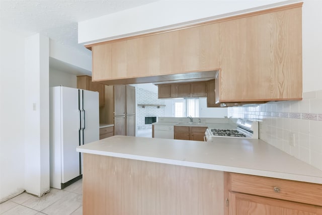 kitchen with sink, kitchen peninsula, white appliances, decorative backsplash, and light brown cabinetry