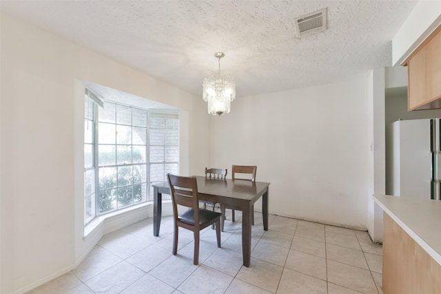 dining room with light tile patterned floors, a textured ceiling, and an inviting chandelier