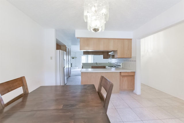 kitchen with range, white refrigerator, decorative light fixtures, and a textured ceiling