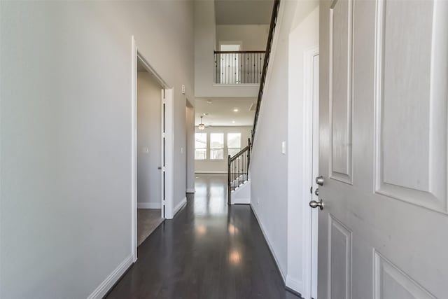 corridor with a towering ceiling and dark wood-type flooring