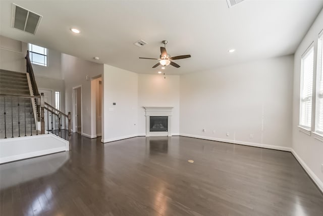 unfurnished living room featuring ceiling fan, dark hardwood / wood-style floors, and plenty of natural light