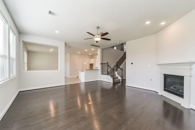 unfurnished living room with dark hardwood / wood-style flooring and ceiling fan