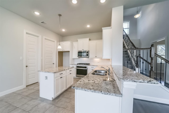 kitchen featuring pendant lighting, sink, kitchen peninsula, and stainless steel appliances