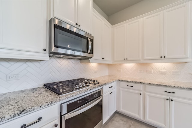 kitchen featuring white cabinets, light stone countertops, stainless steel appliances, and tasteful backsplash