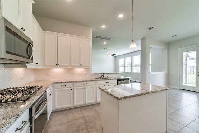 kitchen featuring a center island, white cabinets, sink, light stone counters, and stainless steel appliances