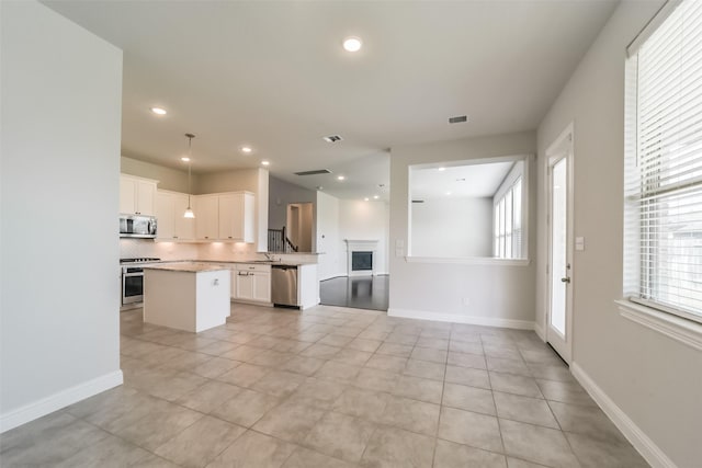 kitchen with stainless steel appliances, sink, light tile patterned floors, white cabinets, and a kitchen island