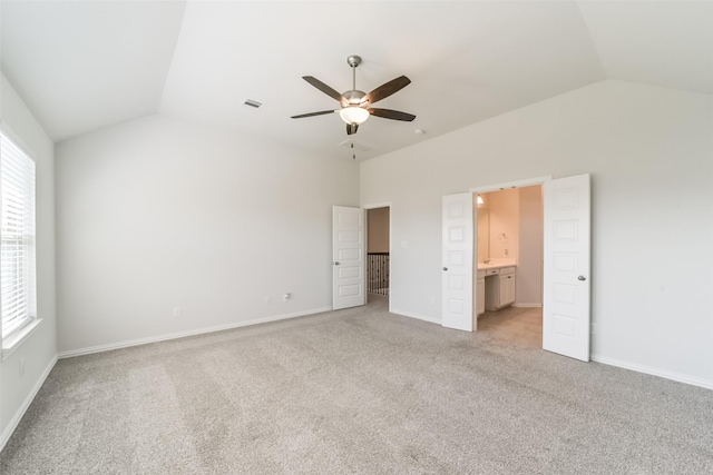 unfurnished bedroom featuring connected bathroom, light colored carpet, ceiling fan, and lofted ceiling