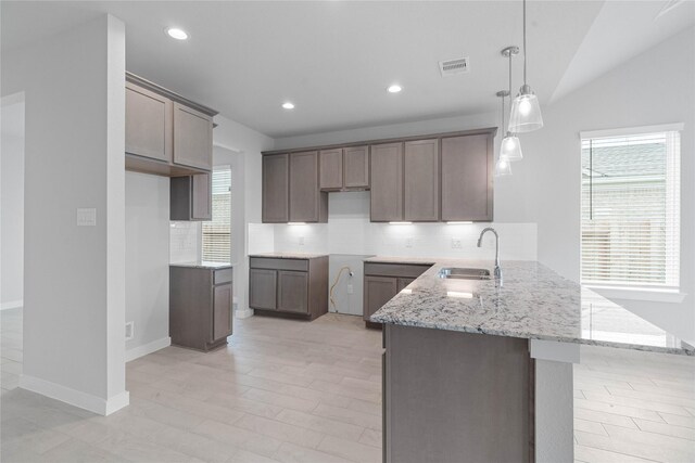 344 Spruce Oak Ln, Waller, TX 77484 - kitchen with a sink, a peninsula, decorative backsplash, light stone counters, and plenty of natural light
