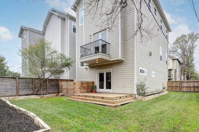 back of property with a yard, a wooden deck, and french doors