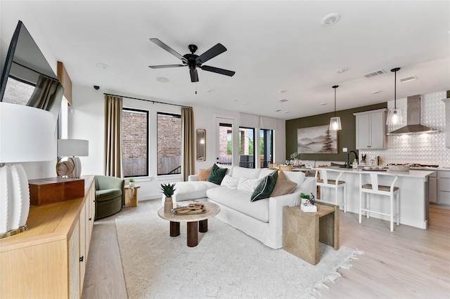 living room featuring ceiling fan, sink, and light hardwood / wood-style flooring