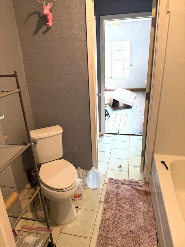 bathroom featuring tile patterned floors, a tub to relax in, and toilet