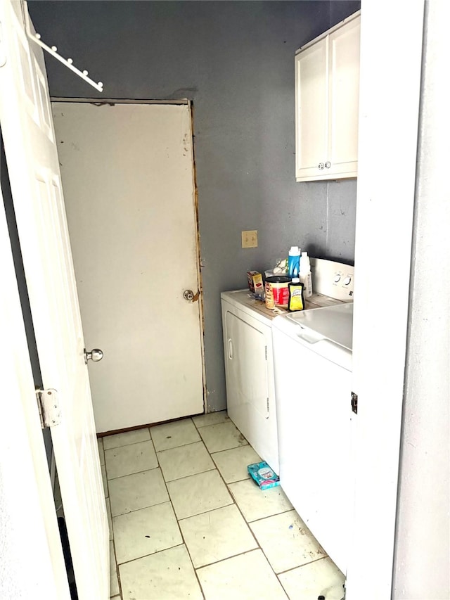 washroom featuring separate washer and dryer, light tile patterned floors, and cabinets